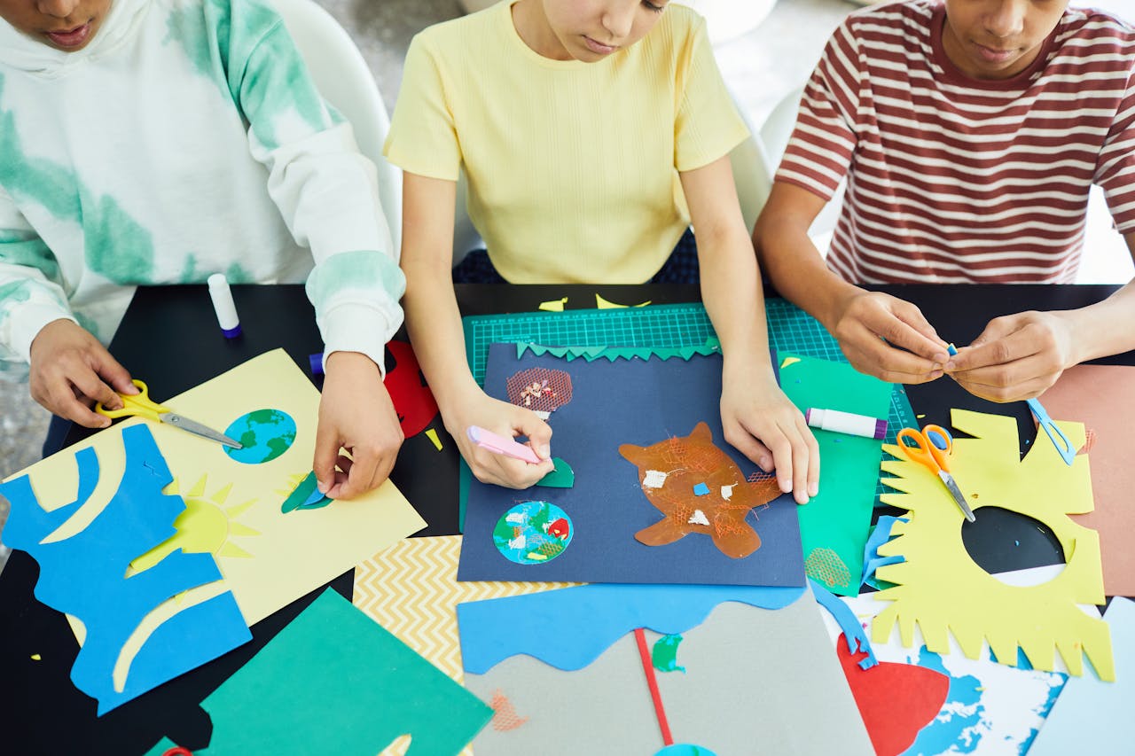 who-we-are Kids enjoy crafting activities using paper and glue in a creative indoor workshop setting.